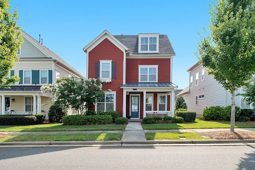 Red, two-story home with white trim and a small porch being sold quick for cash.
