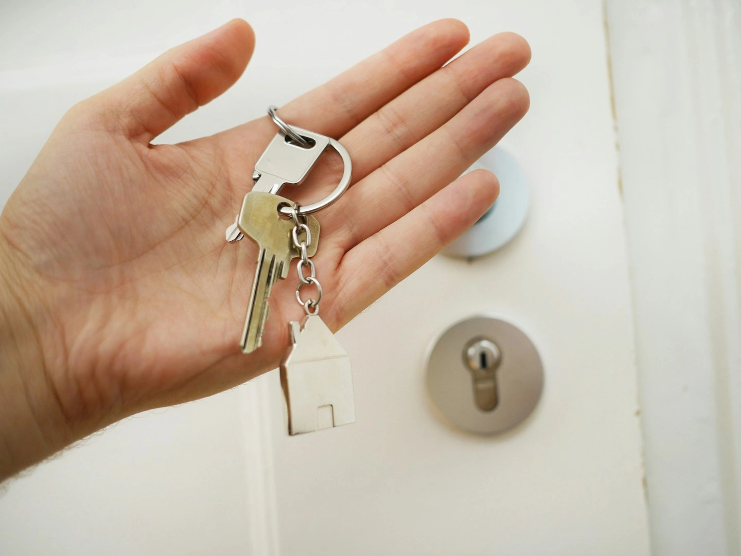 Homeowner holding a keyring with two sets of keys and a keychain shaped like a house.